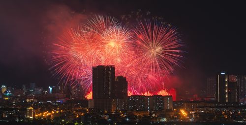 Free Stunning fireworks illuminate the night sky over an urban cityscape, showcasing a vibrant celebration. Stock Photo