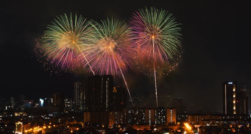 Free Vivid fireworks display illuminated over an urban city skyline during nighttime celebrations. Stock Photo