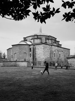Children enjoy a game of soccer next to a historic church in Istanbul, offering a blend of culture and play.