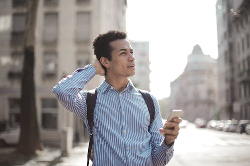Free Thoughtful man using smartphone on street Stock Photo