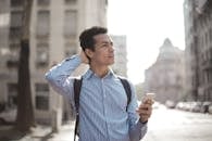 Thoughtful man using smartphone on street