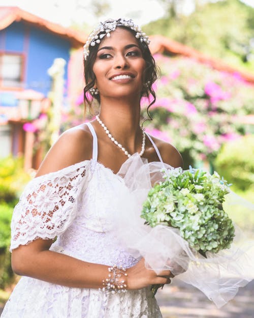 Donna In Vestito Dalla Cinghia Di Spaghetti Del Pizzo Floreale Bianco Che Tiene Il Mazzo Dei Fiori