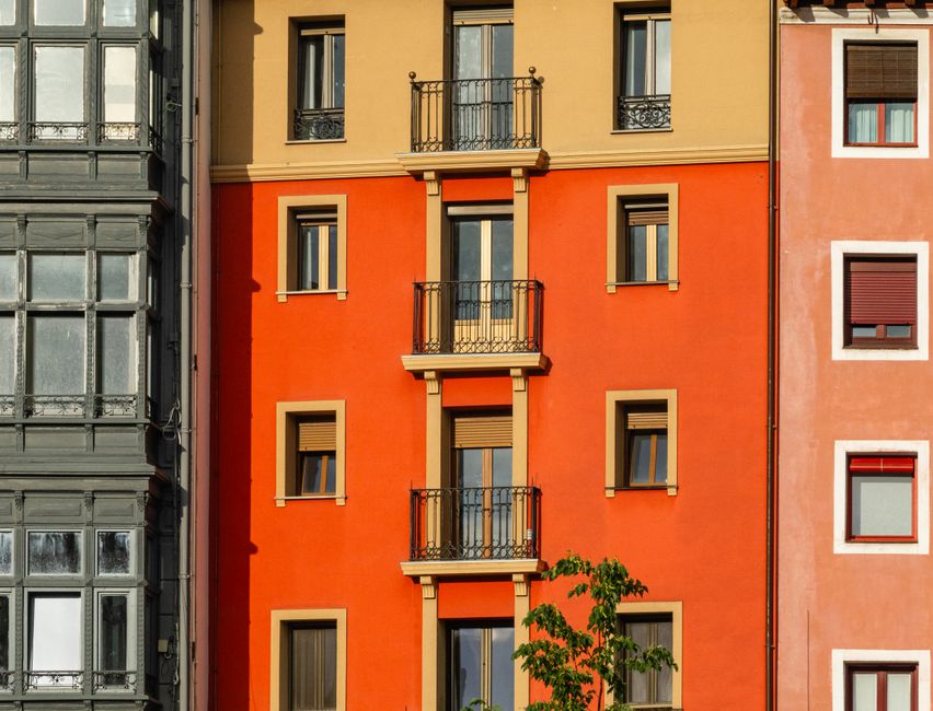 Fachada de un edificio de apartamentos de colores vivos, con elementos arquitectónicos y ventanas que contrastan entre sí.
