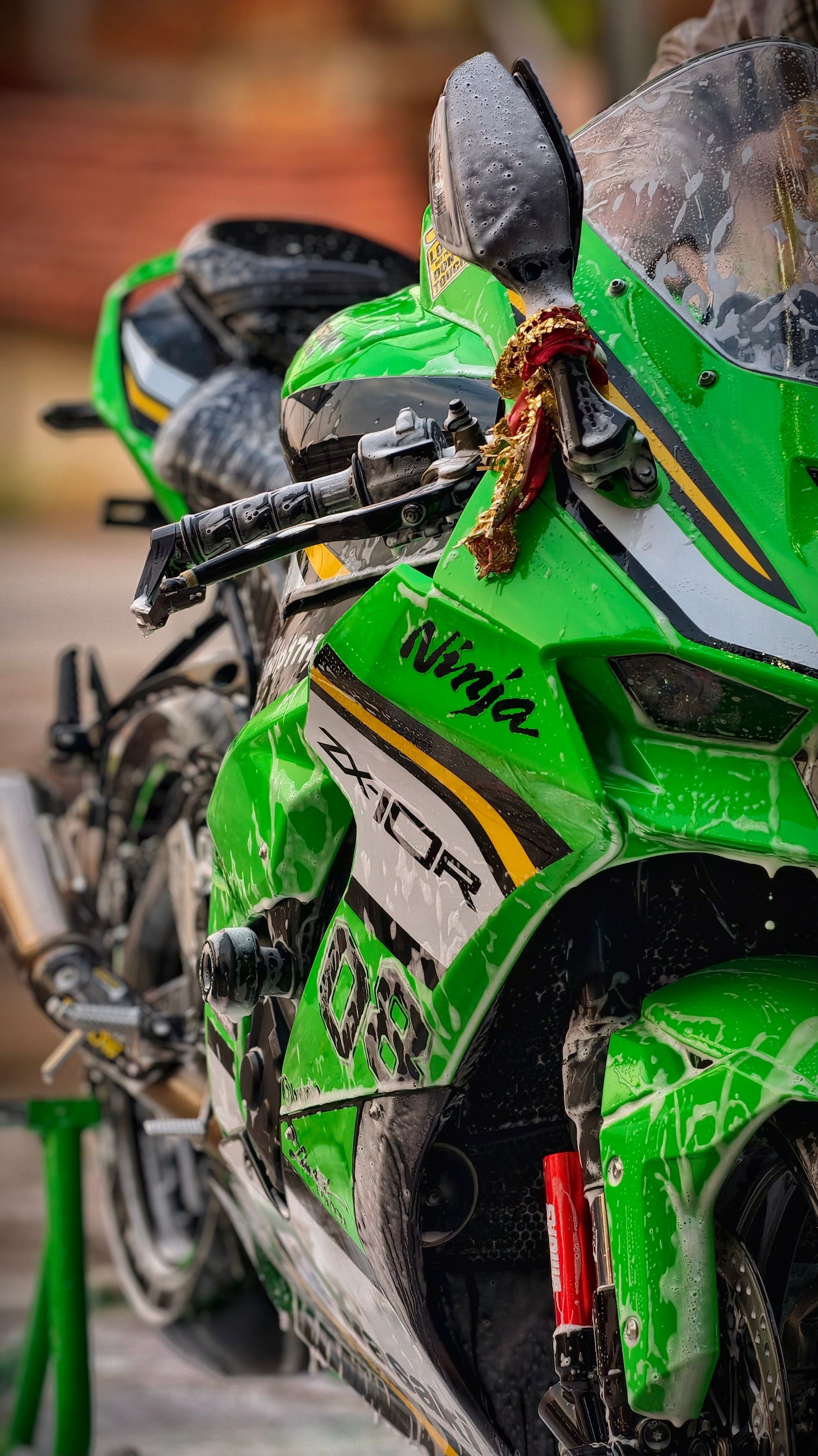 Close-up of a green sports motorcycle with a decorative charm on the handlebar.
