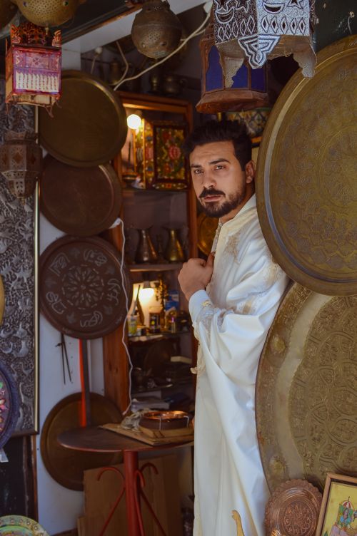 Free A man in traditional attire poses in a handcrafted art shop, showcasing Tunisian culture. Stock Photo