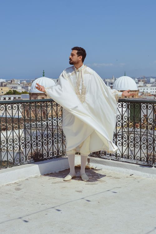 Free Man in traditional clothing standing on a rooftop overlooking a cityscape. Stock Photo