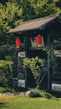 Serene entrance to a traditional Chinese garden adorned with red lanterns and lush greenery.