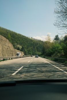 A peaceful drive on a highway through lush green forest hills on a sunny day.
