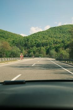 Enjoy a serene drive through lush green mountains under a clear sky.