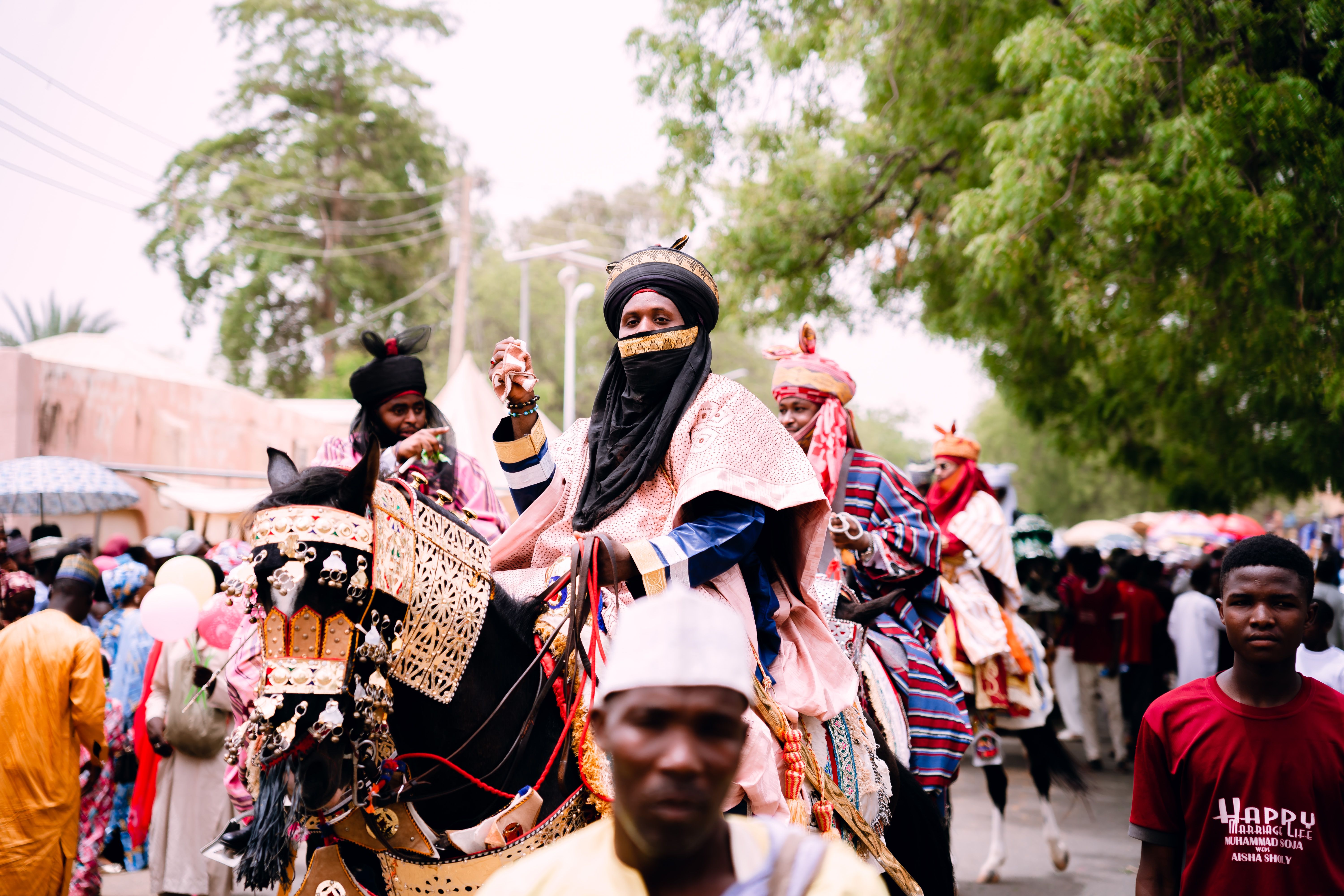 Vibrant scene from a Durbar Festival parade featuring culturally dressed riders and decorated horses.