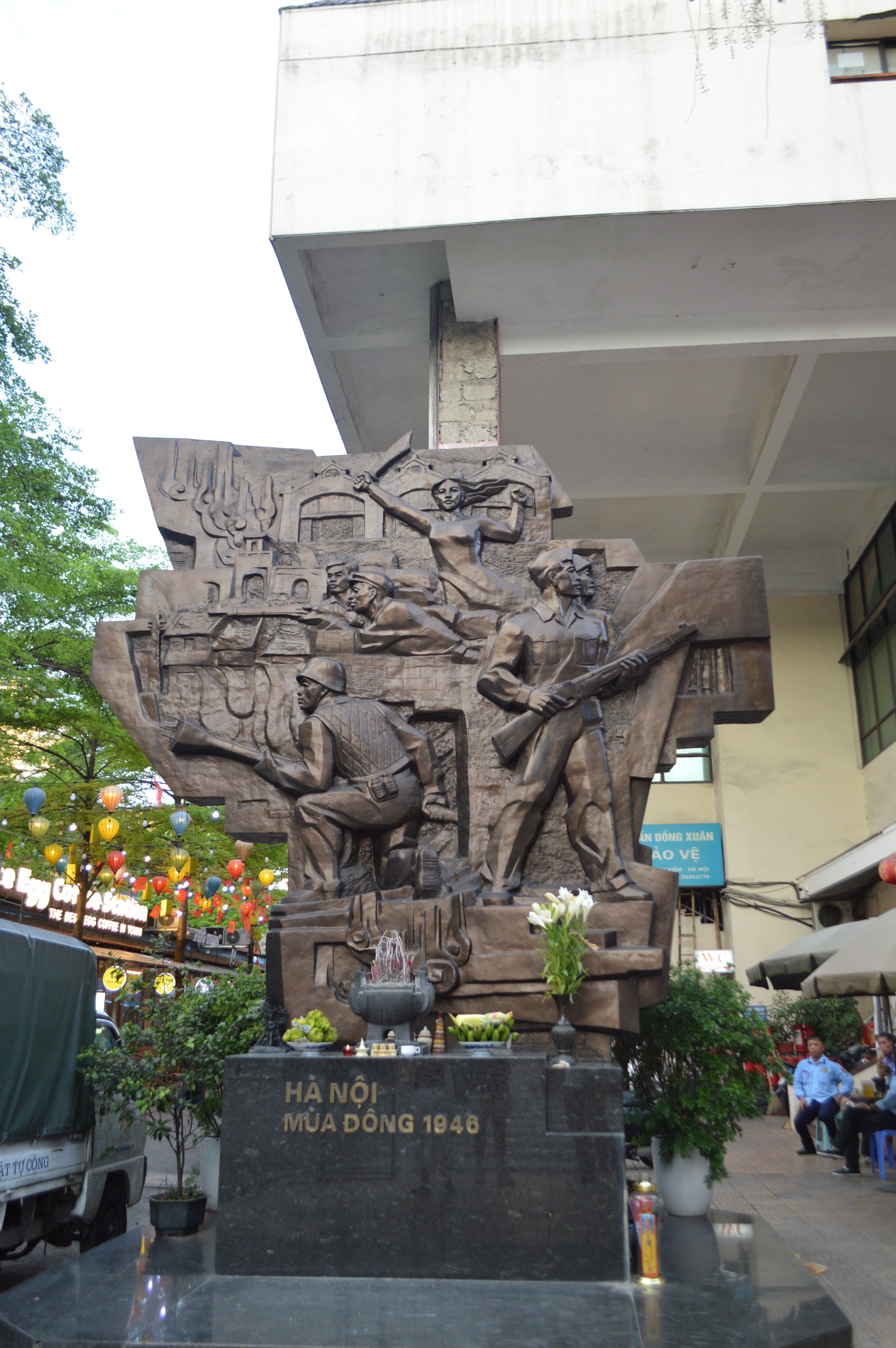 Stone relief monument commemorating Hanoi winter 1946 with surrounding urban context and decorations.