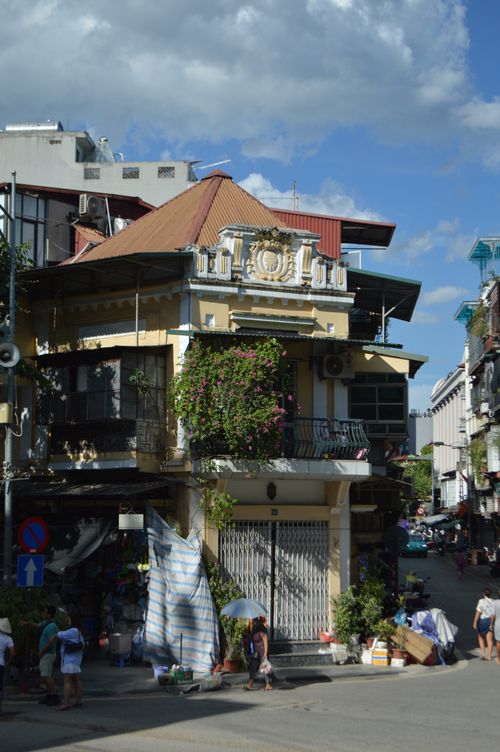 Free A picturesque urban street corner featuring a classic two-story building with balconies and lively surroundings. Stock Photo