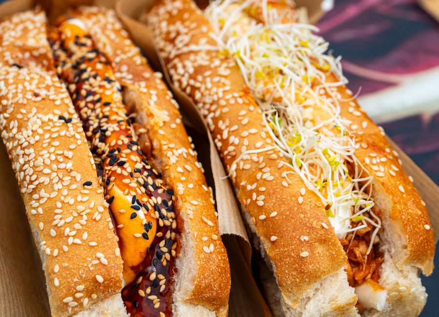Two loaded craft hot dogs on sesame seed buns