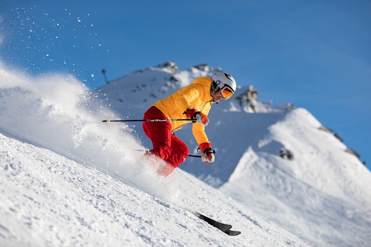 Person In Yellow Jacket And Red Pants Skiing