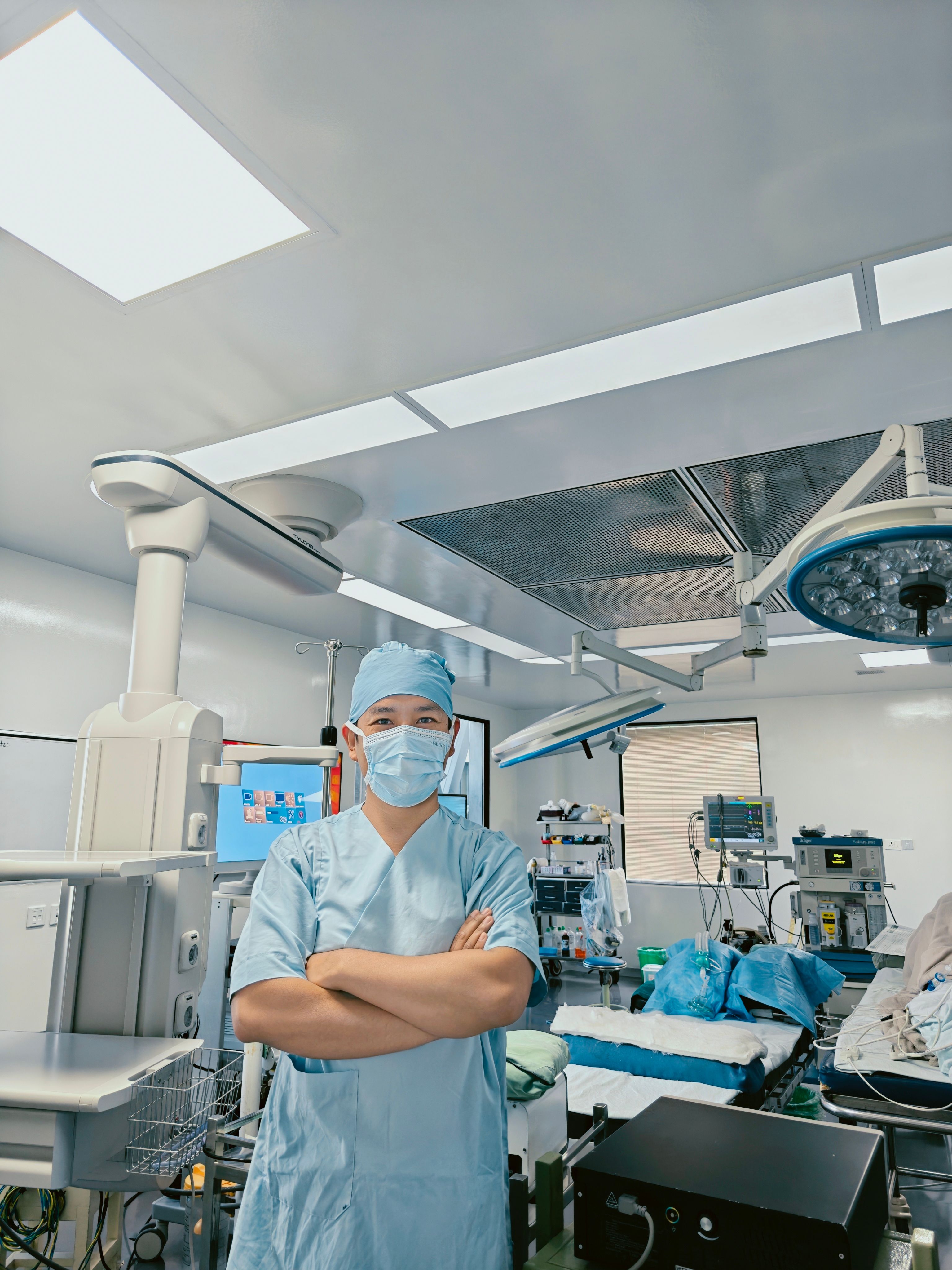 Surgeon standing confidently in a modern, equipped operating room, ready for surgery.