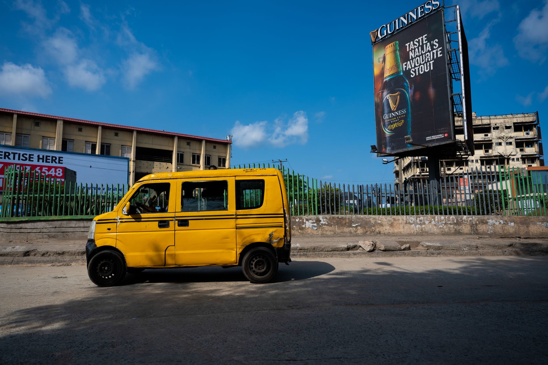 Dynamic street scene in Lagos featuring the iconic yellow danfo bus and urban backdrop.