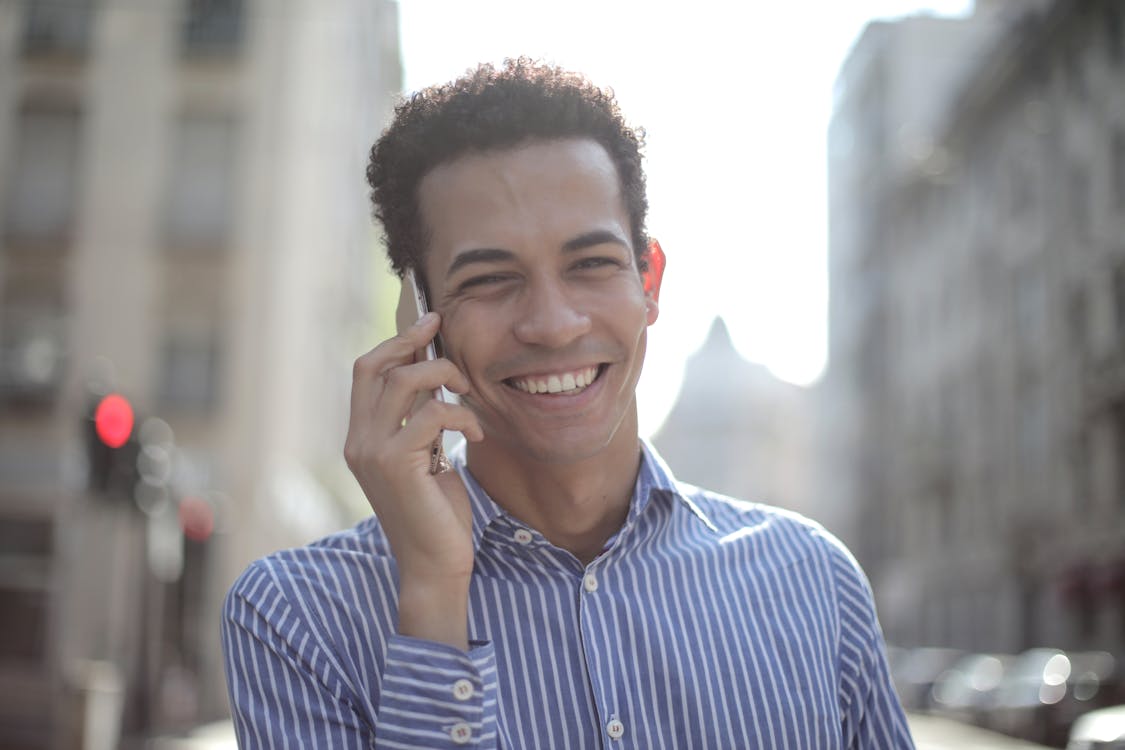 Free Cheerful Ethnic Man Talking On Smartphone Stock Photo