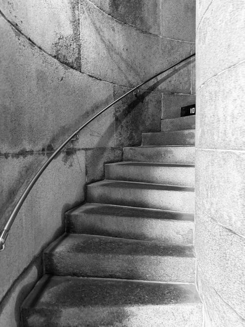 Free Black and white photo of a curved stone staircase with a metal railing. Stock Photo