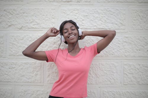 Cheerful black woman with earphones dancing