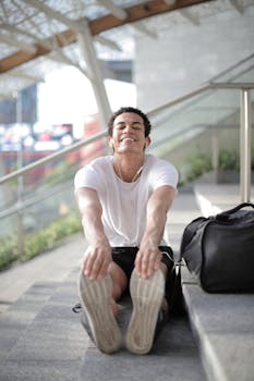 一个穿着白衬衫的男人快乐地在楼梯上伸展身体，享受着阳光明媚的一天