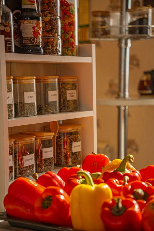 Free Vibrant red, yellow bell peppers with spice jars in a sunlit kitchen setting. Stock Photo