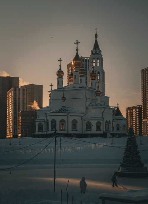 Free A stunning cathedral surrounded by snow at sunset, capturing a serene winter ambiance. Stock Photo