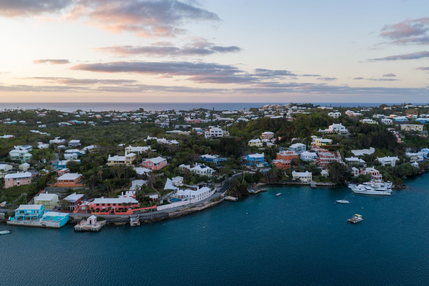 Aerial view of pastel-coloured Bermudian houses along the coast at sunset