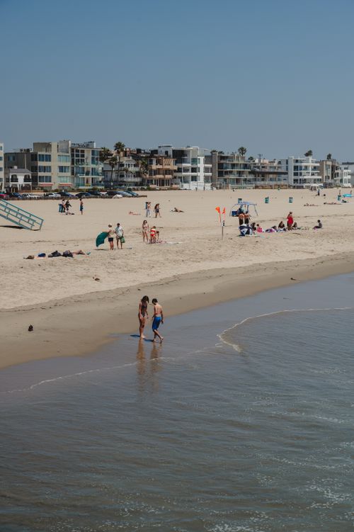 Free A lively day at the beach with people enjoying the sun and ocean waves. Stock Photo