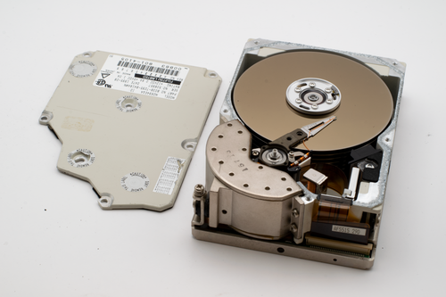 Free Close-up of an opened vintage hard disk drive with its cover removed, exposing internal components. Stock Photo