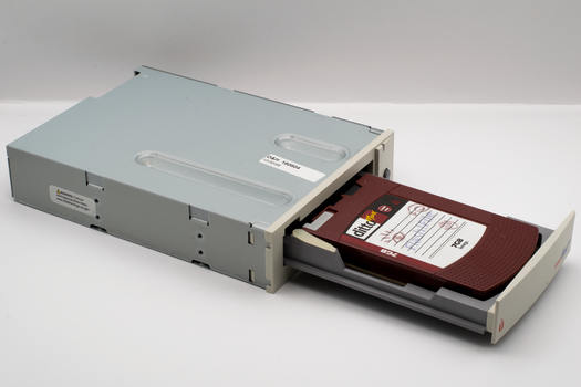 Vintage computer backup tape drive with open tray, showcasing retro technology.