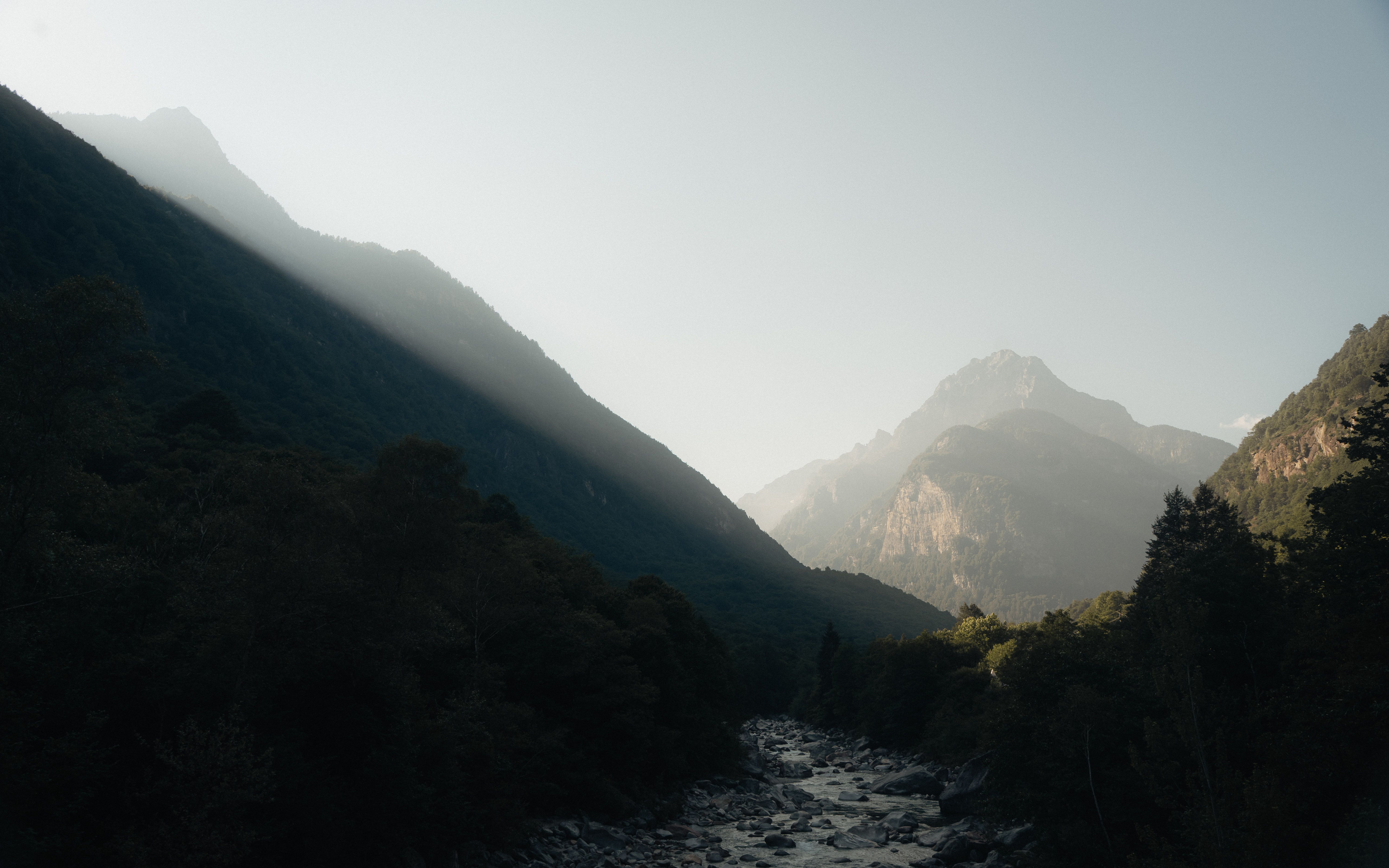 Captivating view of Ticino's mountainous landscape with sunlight streaming through the peaks.