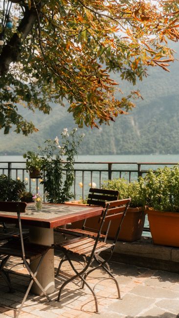 Outdoor dining setup with a lake view and autumn foliage in Ticino, Switzerland.