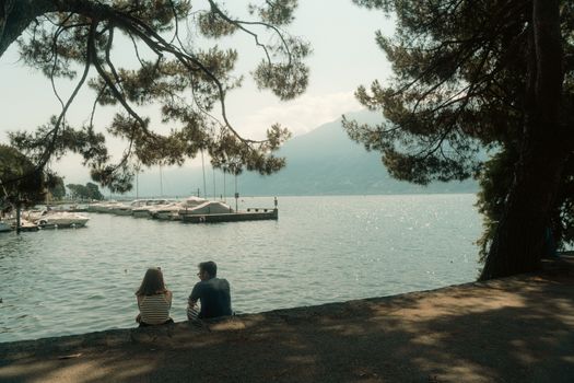 Couple enjoying a serene lakeside view with mountains in Ticino, Switzerland.