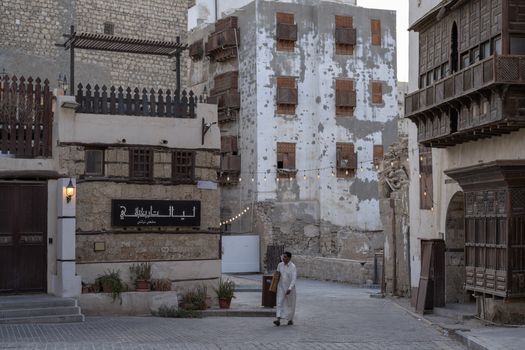 A man walks along a historic street in Al-Balad, Old Jeddah, showcasing traditional architecture.