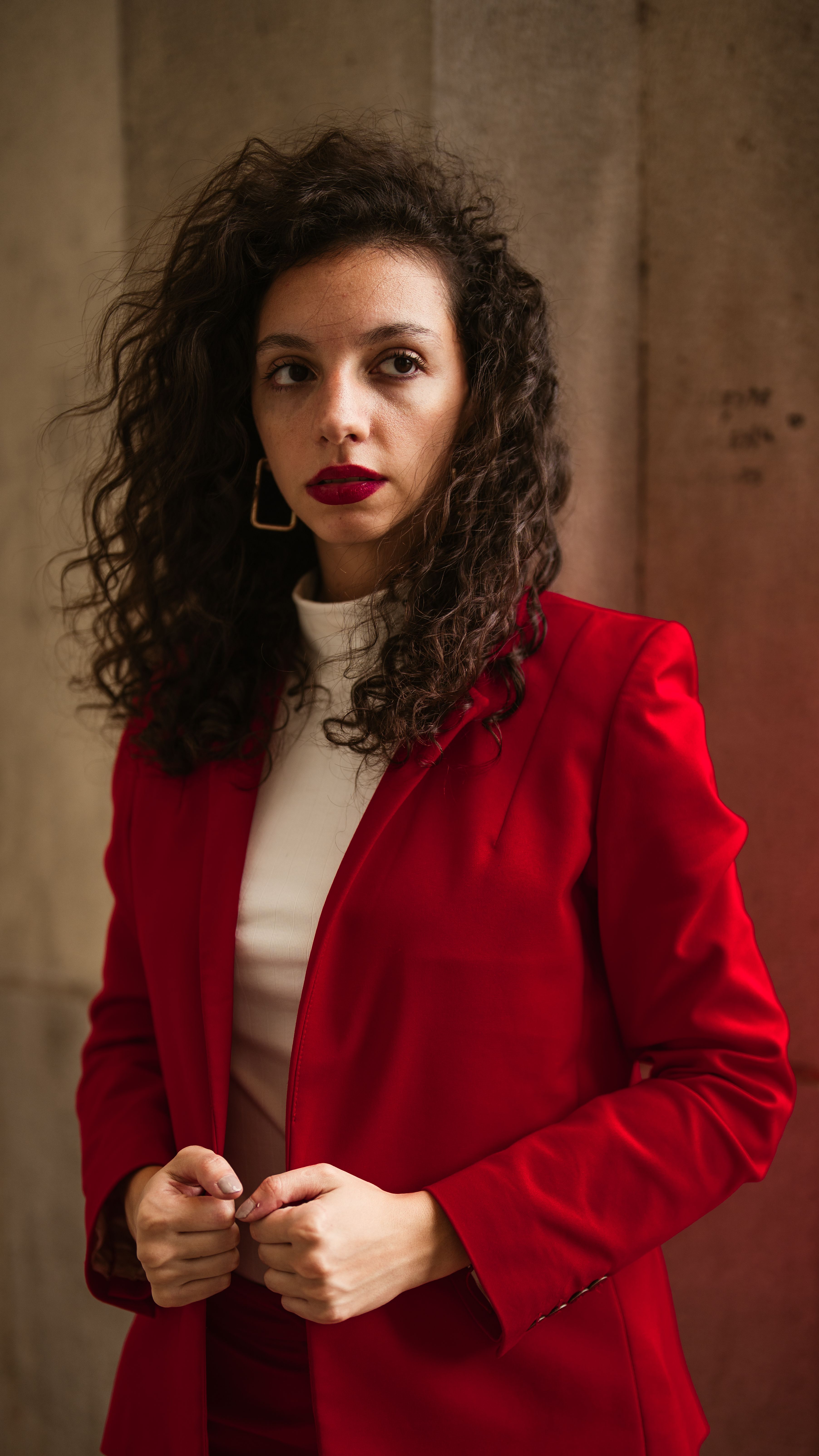 Portrait of a woman in a striking red suit, exuding confidence and style.