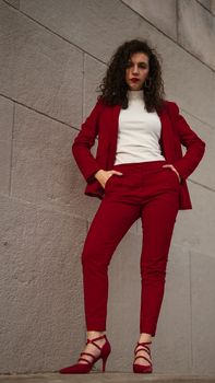 Fashionable woman posing in a stylish red suit against urban backdrop in Buenos Aires.