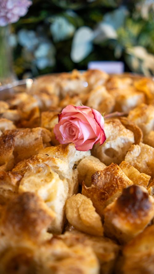 Free Golden brown bread pudding adorned with a delicate pink rose, creating a unique culinary presentation. Stock Photo