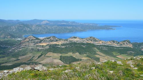 Free A breathtaking view of a coastal mountain range with lush fields and the blue sea beyond. Stock Photo