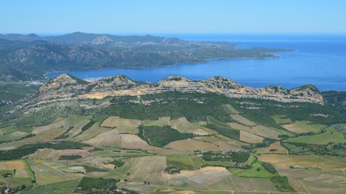 Free Stunning aerial view of a coastal mountain range and lush countryside fields. Stock Photo