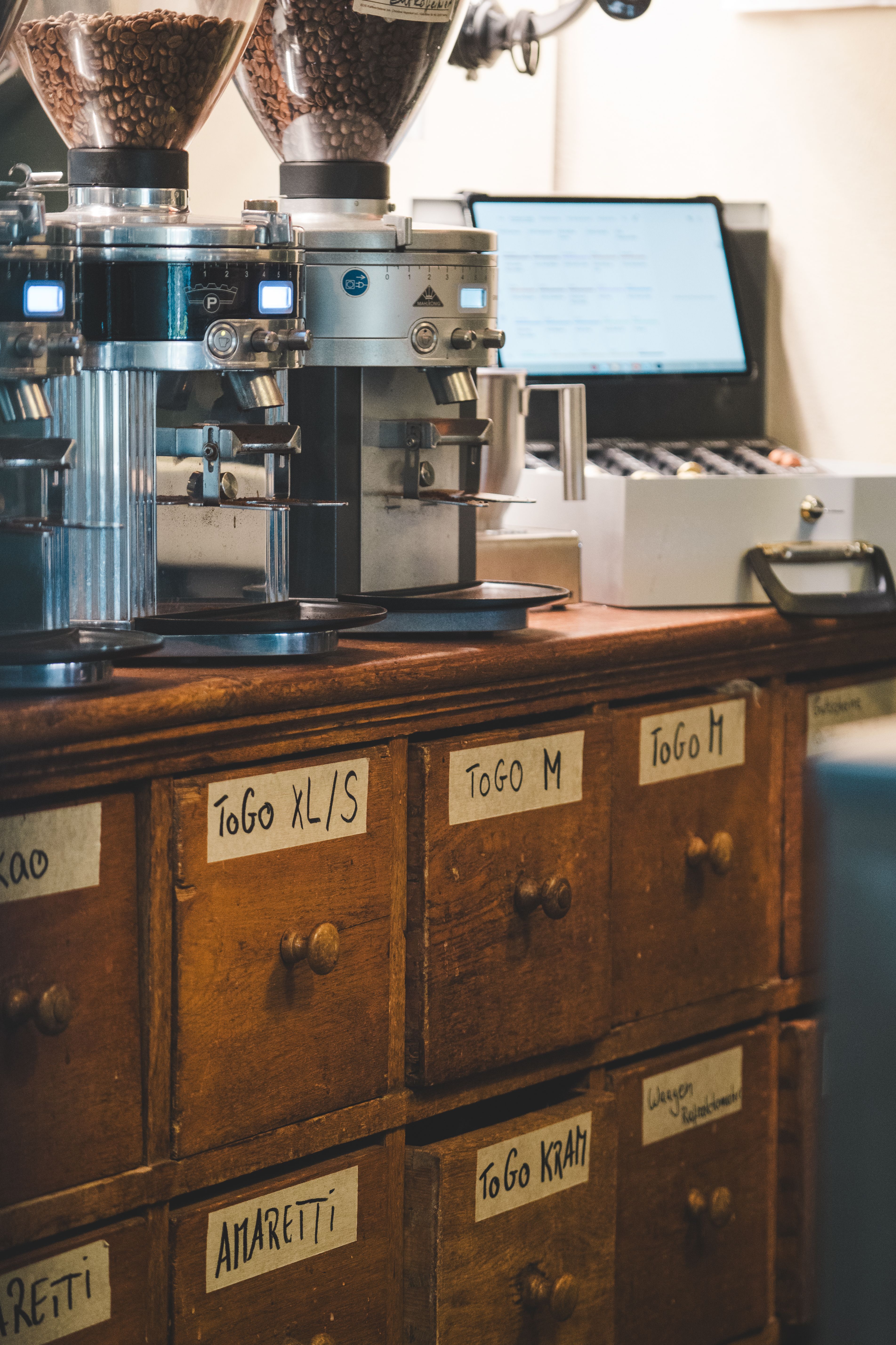 open pull-out drawer under a kitchen counter holding coffee grinder and filters