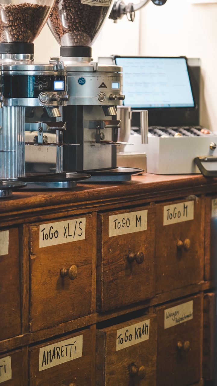 open pull-out drawer under a kitchen counter holding coffee grinder and filters