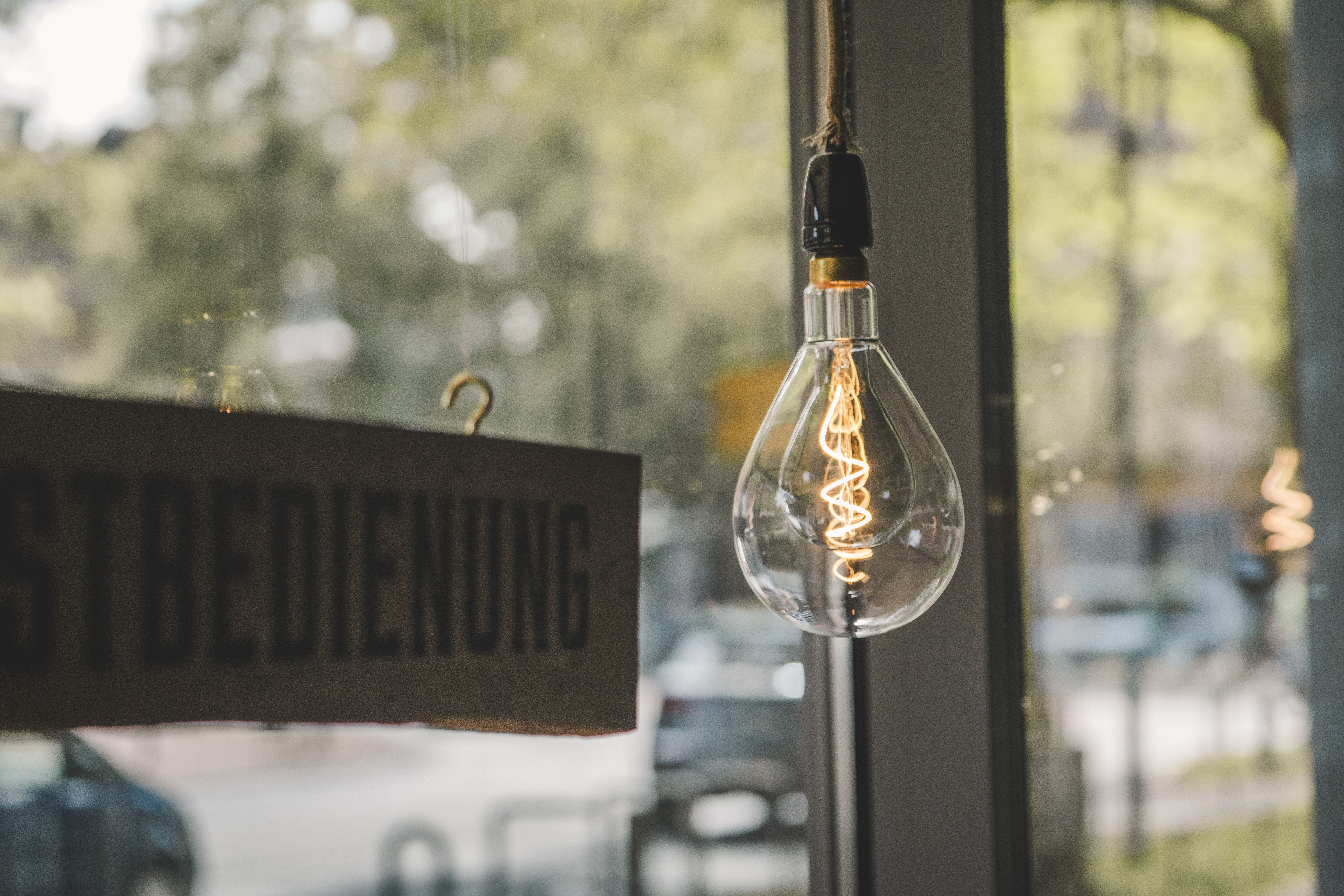 Close-up of an Edison bulb hanging in a cozy urban café, providing a warm ambiance.