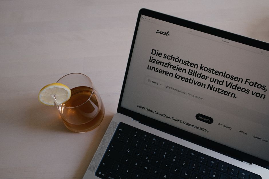 A laptop on a desk beside a glass of lemon tea, perfect for working or studying.