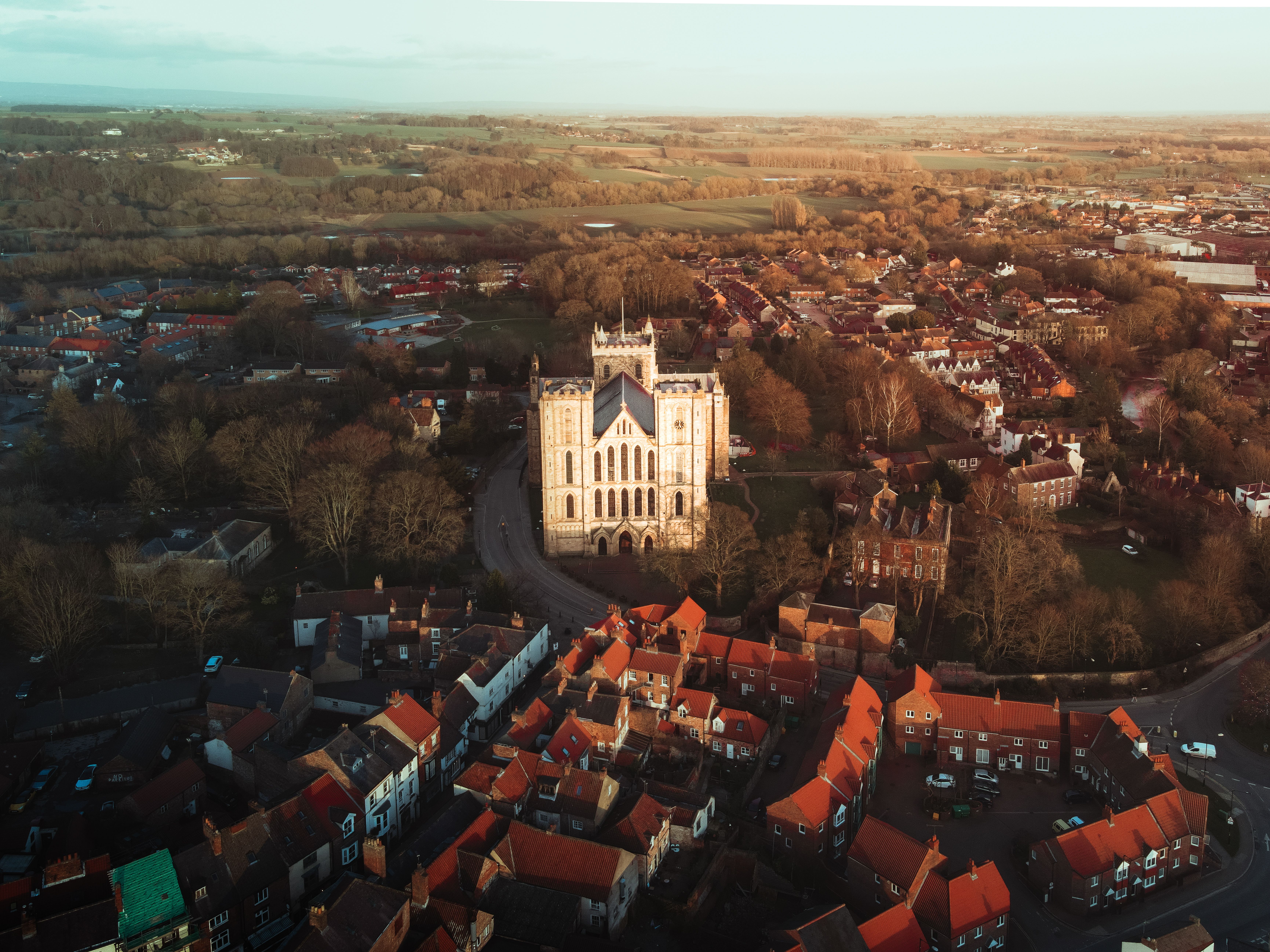 Stunning aerial view of Ripon Cathedral surrounded by a quaint village at sunset.