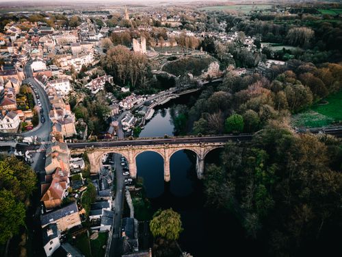 Free A stunning aerial view of a townscape featuring a historic stone bridge and lush greenery during the day. Stock Photo