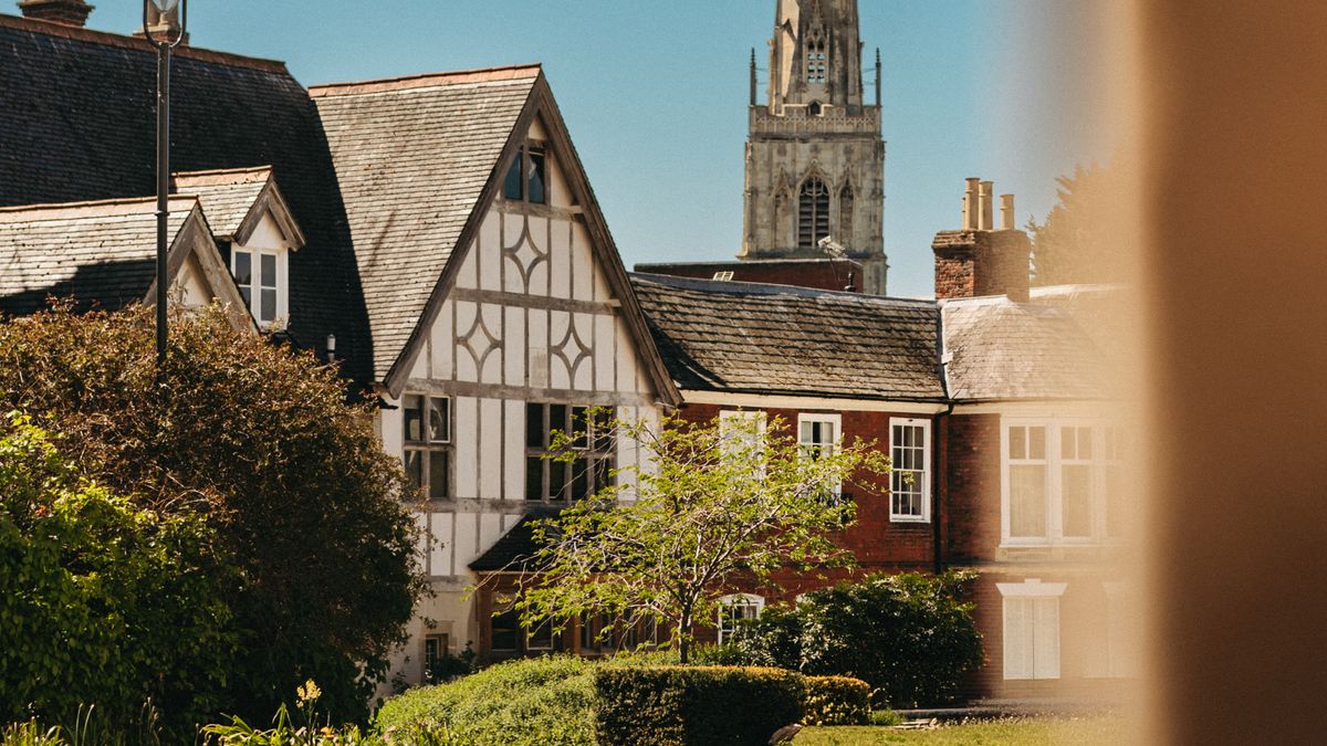 Timber-framed houses and a church tower on a sunny day in Gloucester