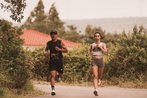 Free Two athletes jogging on an outdoor trail during a marathon, surrounded by greenery. Stock Photo