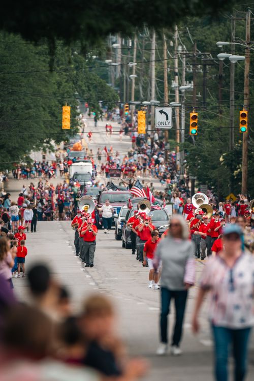 Free A vibrant city street parade featuring a marching band and crowd celebrating a festive event. Stock Photo