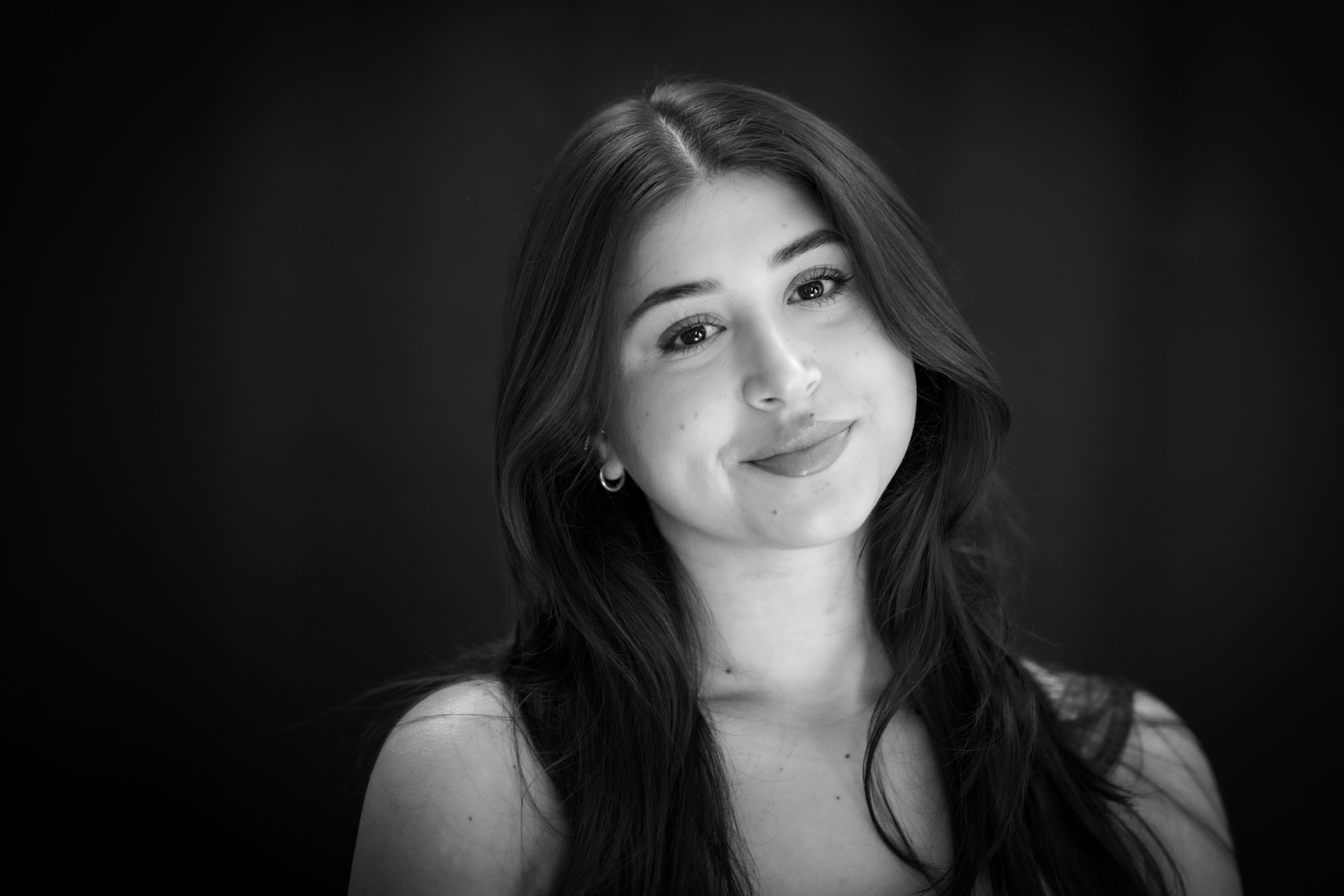 Elegant black and white portrait of a young woman smiling with long hair.