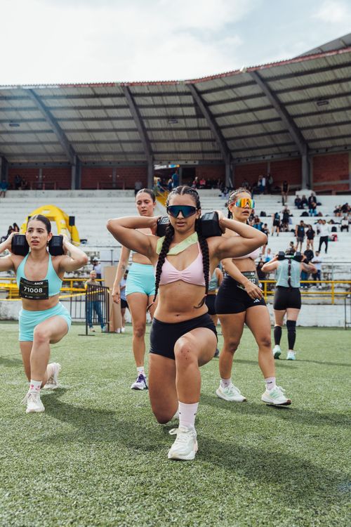 Free Women performing a fitness workout at an outdoor stadium, showcasing strength and teamwork. Stock Photo